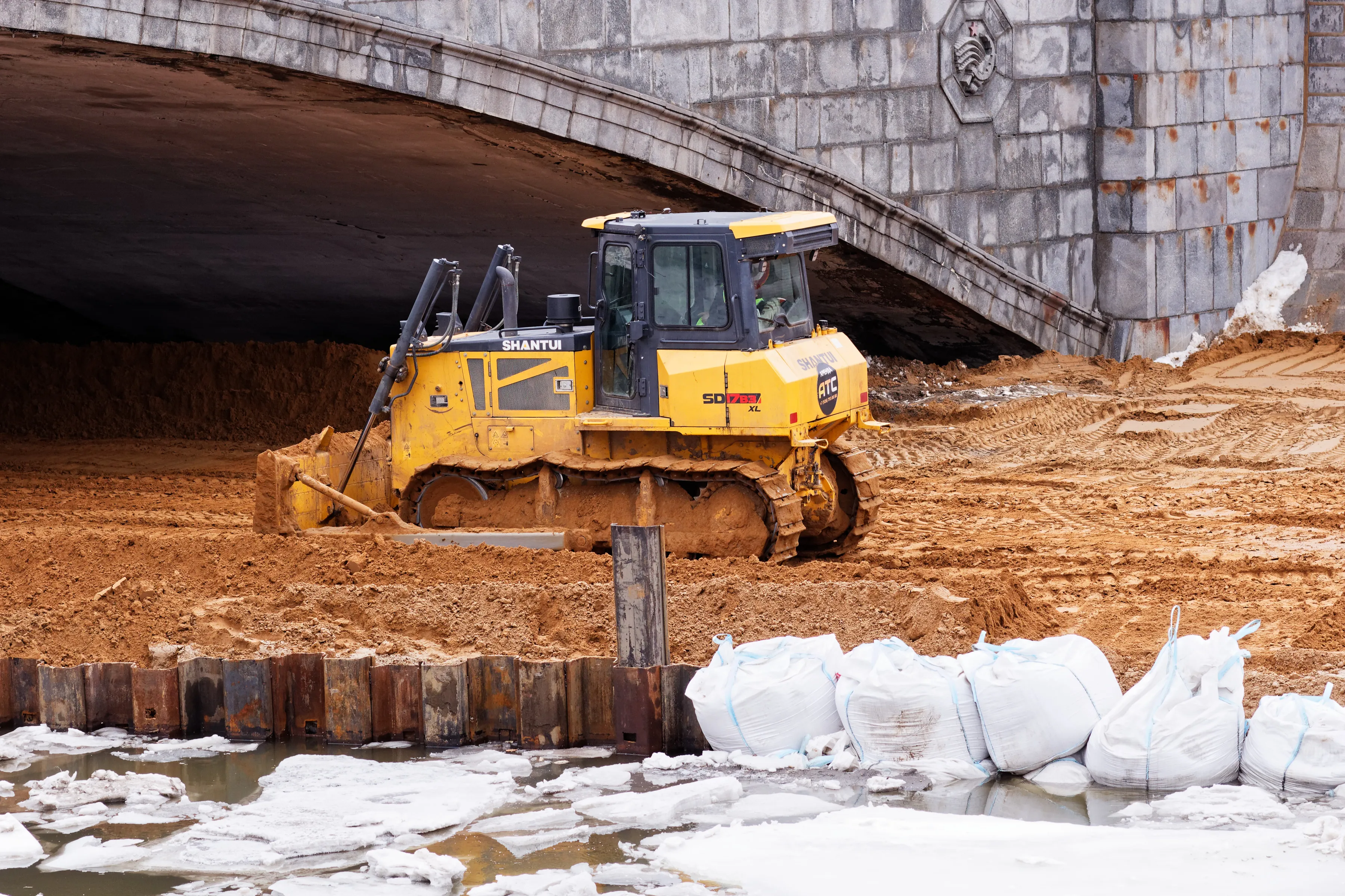 Bulldozer working on earthworks beside a bridge
